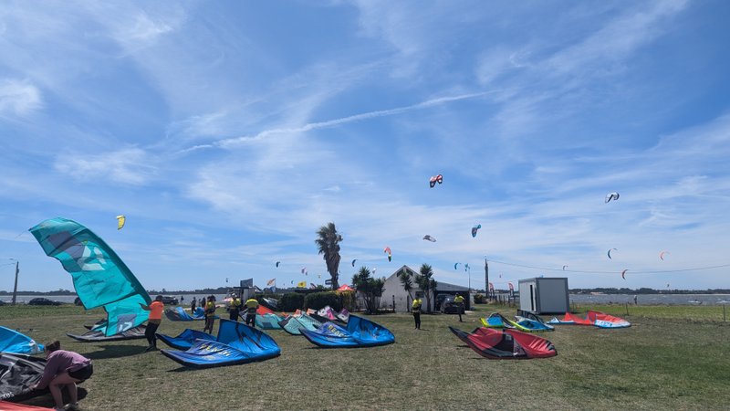 Kitesurfers prepare their gear on a grassy rigging area at Murtosa with the water visible in the background. — Murtosa (Ria de Aveiro), Murtosa, Portugal