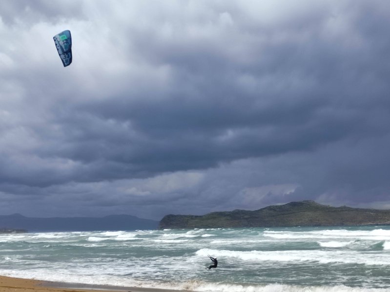 A kitesurfer riding in wavy conditions at Stalos beach.