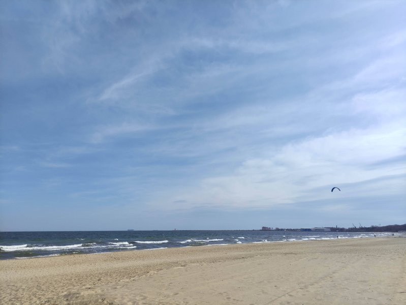 Wide view of the sandy beach and sea at Gdańsk with a kite in the air.
