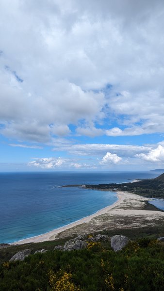 Elevated view of the sandy beach and clear blue waters of Ancoradoiro bay under a cloudy sky. — Ancoradoiro (Louro), Muros, Galicia, Spain