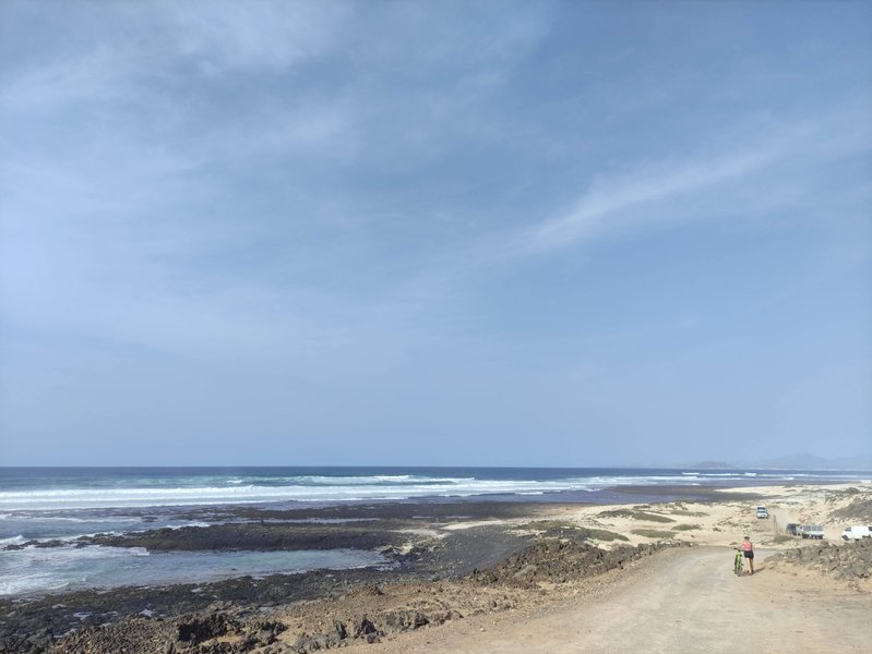 A wide view of the rocky coastline and breaking waves at Derecha de los Alemanes.
