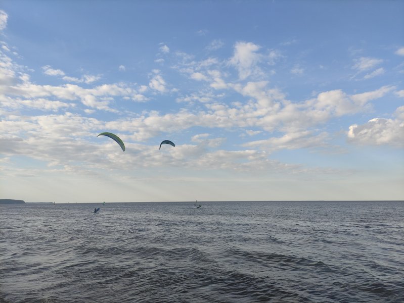 Kitesurfers on the water under a partly cloudy sky in Sopot.