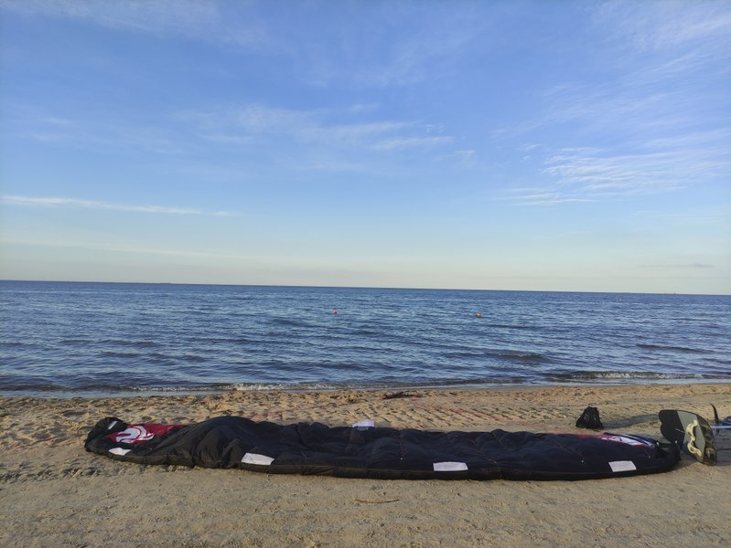 Kitesurfing gear laid out on the sandy beach of Sopot with the Baltic Sea in the background.
