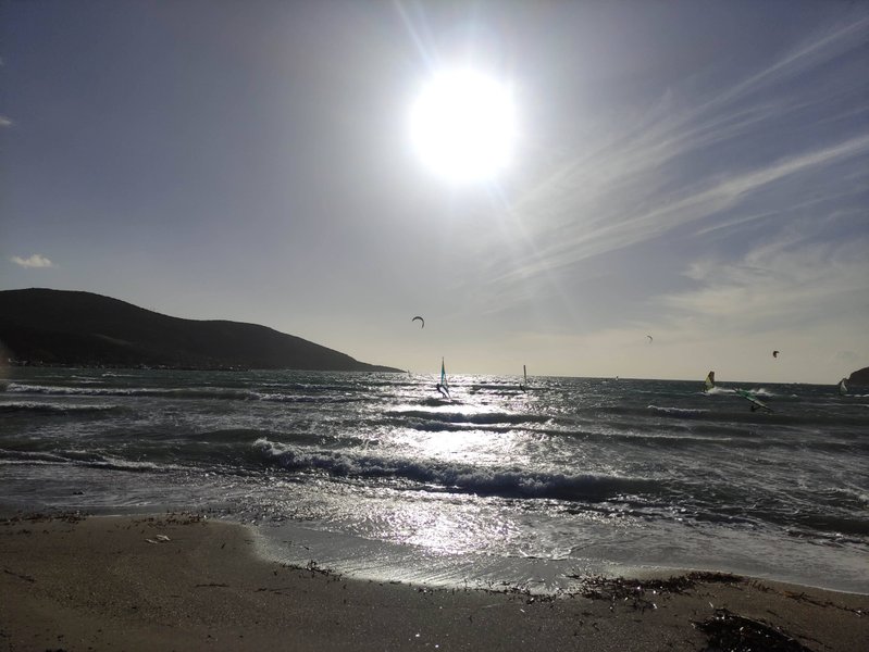 A view of the bay at Anavissos with windsurfers and kitesurfers on the water.