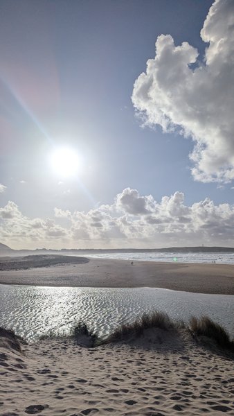 A sunny view of a wide sandy beach with a lagoon, leading to the ocean under a bright sky with scattered clouds. — Valdoviño (Da Frouxeira), Valdoviño, Galicia, Spain