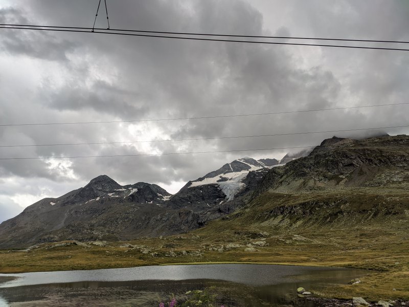 A view of the mountains and a small lake at Bernina Pass under heavy cloud cover. — Bernina Pass (Maloja), Pontresina, Grisons, Switzerland