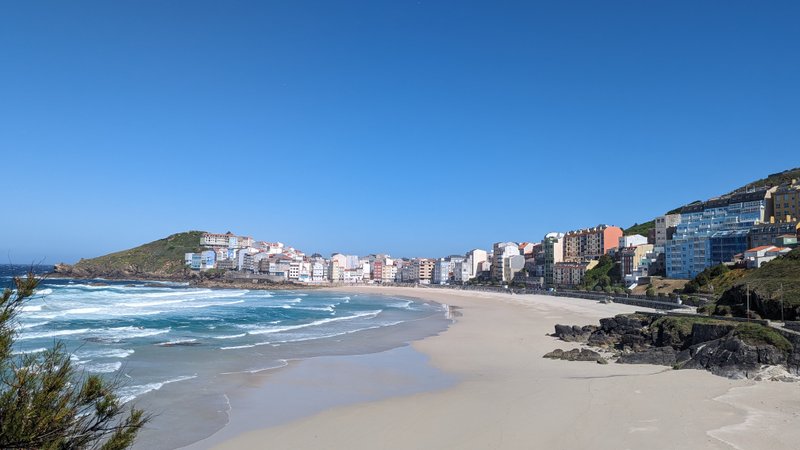 A wide view of Playa de Malpica showing the sandy beach, surf, and the town's buildings. — Praia de Malpica (Malpica), Malpica, Galicia, Spain