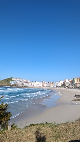 A wide view of the sandy beach and town at Playa de Malpica under a clear blue sky. — Praia de Malpica (Malpica), Malpica, Galicia, Spain
