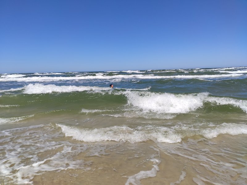 Waves breaking on the beach at Debki under a clear blue sky.