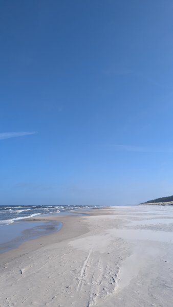 A wide, clear view of the sandy beach and the Baltic Sea at Debki.