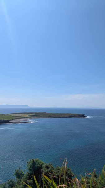 A wide view of the Muckros Peninsula coastline and calm blue ocean under a clear sky. — Muckros (Península de Muckross), Ireland