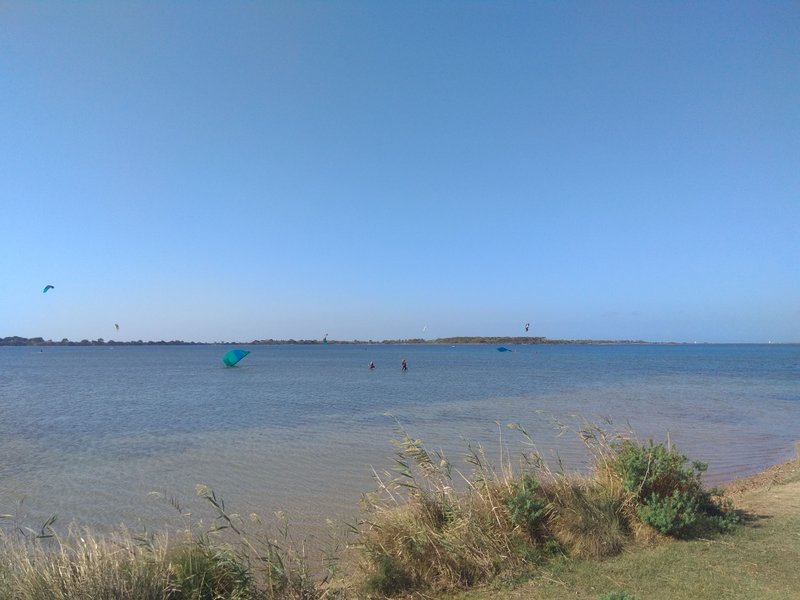 Kitesurfers in the shallow waters of Lo Stagnone lagoon under a clear blue sky. — Lo Stagnone (Marsala), Marsala, Sicily, Italy