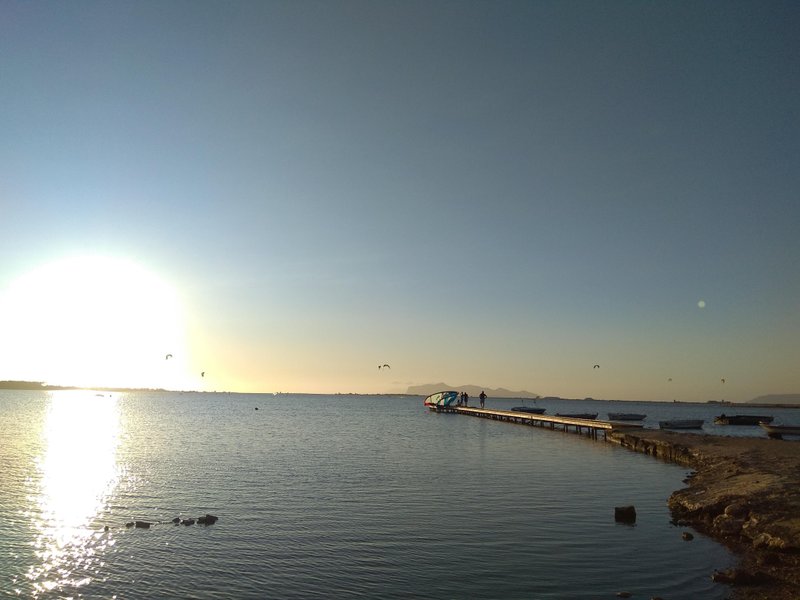 Sunset over the lagoon at Lo Stagnone with a wooden pier and kites in the distance. — Lo Stagnone (Marsala), Marsala, Sicily, Italy
