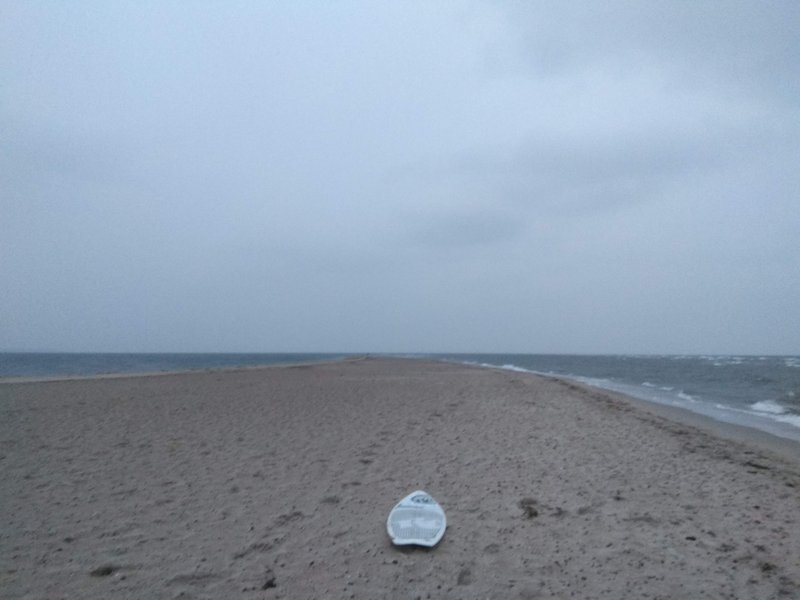 A view along the Rewa sandbar with a surfboard in the foreground on a cloudy day. — Cypel (Rewa), Rewa, Pomeranian Voivodeship, Poland