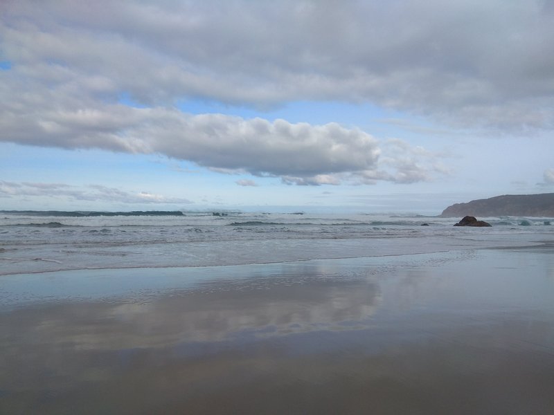 A wide view of the beach and waves at Praia do Guincho under a cloudy sky. — Praia do Guincho (Cascais), Cascais, Portugal