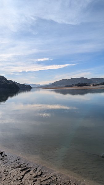 A wide view of a calm body of water surrounded by hills under a blue sky. — Laida (Urdaibai), Sukarrieta, Autonomous Community of the Basque Country, Spain