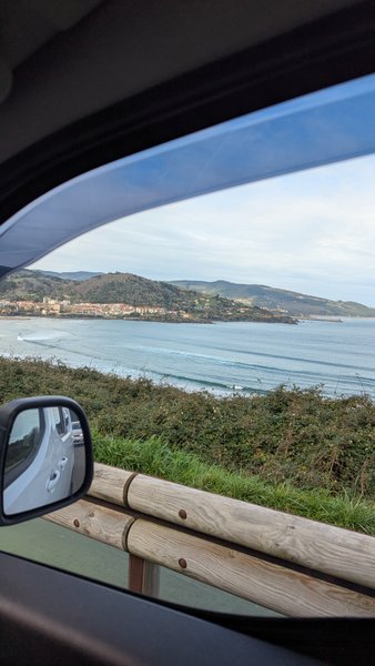 A view of the bay with waves and a coastal town from inside a car. — Laida (Urdaibai), Sukarrieta, Autonomous Community of the Basque Country, Spain