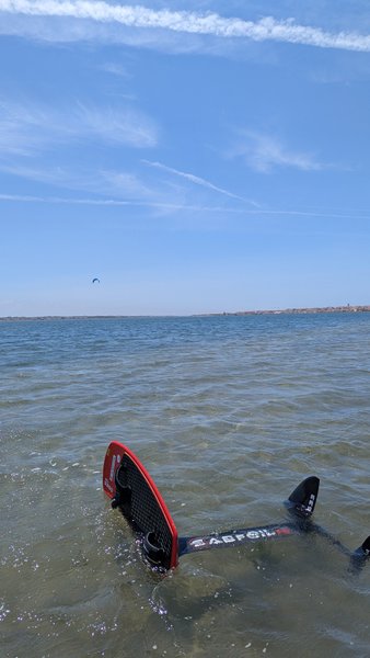 A kite foil board floats in the shallow water of the Ria de Aveiro under a clear blue sky. — Costa Nova - Biarritz (Ria de Aveiro), Ílhavo, Portugal