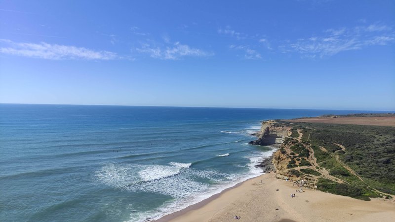 A high-angle view of Ribeira das Ilhas beach showing the breaking waves and coastline.