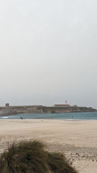 A view across the sand at Playa Chica in Tarifa towards the historic fortifications with a kite in the air. — Playa Chica (Tarifa), Tarifa, Andalusia, Spain