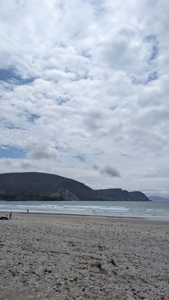 A wide, pebbly beach stretches towards the sea with distant hills under a cloudy sky. — Keel (Ilha de Achill), County Mayo, Westport-Belmullet Municipal District, Ireland