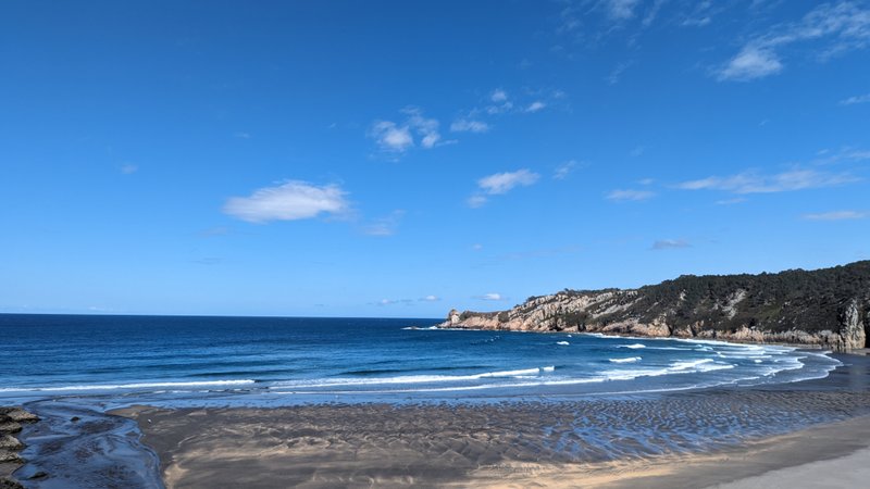 A wide view of Playa de Barayo with calm waves and dark sand under a clear blue sky. — Playa de Barrayo (Otur), Valdés, Asturias, Spain