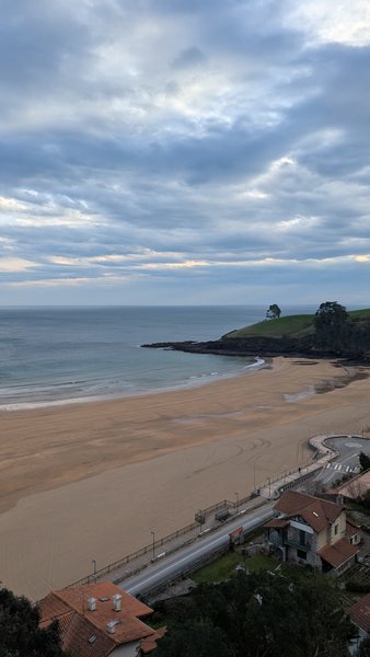 An elevated view shows the wide sandy beach and ocean at Carraspio under a cloudy sky. — Praia de Carraspio (Mendexa), Mendexa, Autonomous Community of the Basque Country, Spain