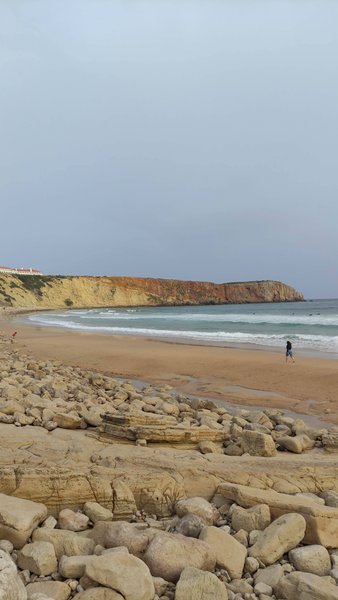 A view of the sandy beach and cliffs at Mareta under an overcast sky.