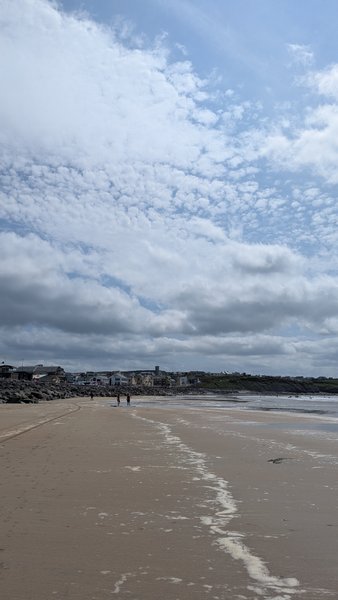 A wide view of Lahinch beach with the town in the distance under a cloudy sky. — Lahinch (Clare), Ireland