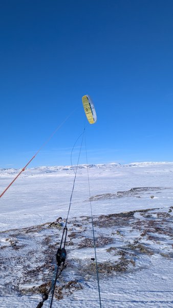 A yellow kite flies over a vast snow-covered landscape on a clear day. — Skiftessjøen (Eidfjord), Vestland, Norway
