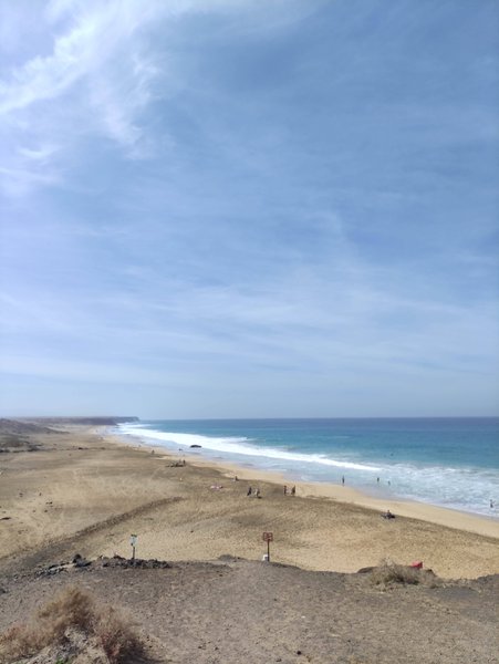 A wide view of the sandy beach and turquoise water at El Cotillo.