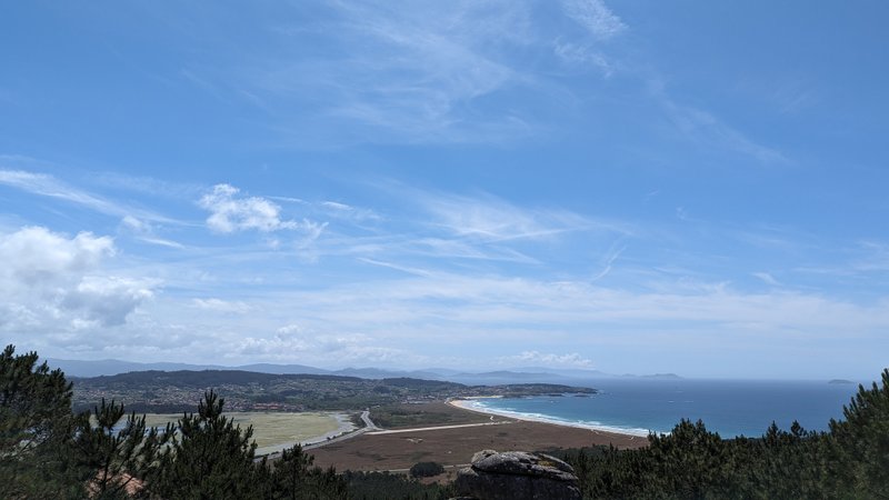 A wide-angle landscape view of the Mexilloeira coastline and beach under a clear blue sky. — Mexilloeira (Balea), O Grove, Galicia, Spain