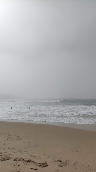 A foggy view of surfers in the water at Praia do Peixe. — Praia do Peixe (Ericeira), Ericeira, Portugal