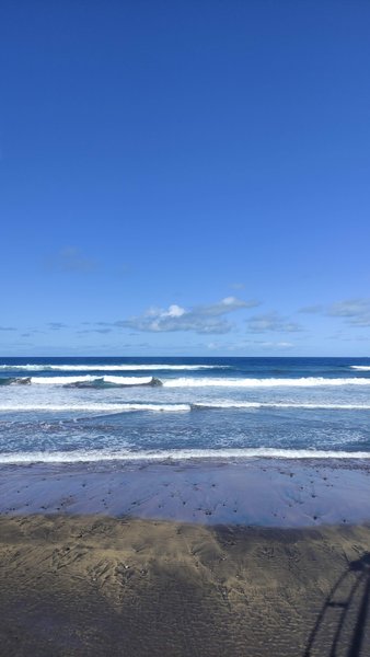 Waves breaking on the dark sand beach at La Cicer under a clear blue sky. — La Cicer (Los Giles - East), Las Palmas, Canary Islands, Spain