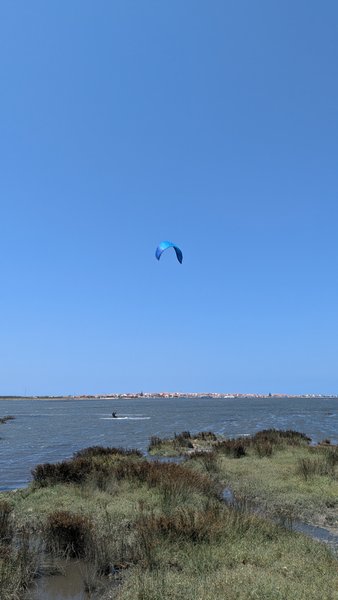 A kitesurfer riding on the water at Ervas, Ria de Aveiro, under a clear blue sky. — Ervas (Ria de Aveiro), Ílhavo, Portugal