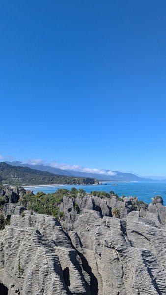 View of the Pancake Rocks and Punakaiki coastline under a clear blue sky.