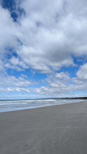 A wide, sandy beach meets the ocean under a partly cloudy sky. — Ocean View (Brighton), Brighton, Otago, New Zealand