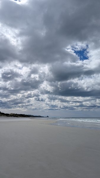 A wide sandy beach meets the ocean under a cloudy sky with distant headlands. — Ocean View (Brighton), Brighton, Otago, New Zealand