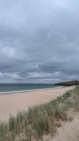 A wide view of the sandy beach and clear water at Doogort under a cloudy sky. — Doogort (Achill Island), County Mayo, Westport-Belmullet Municipal District, Ireland