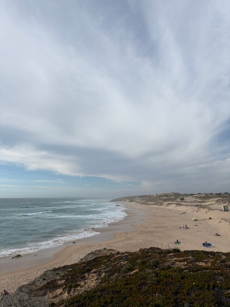 An elevated view of the wide sandy beach and waves at Malhão.