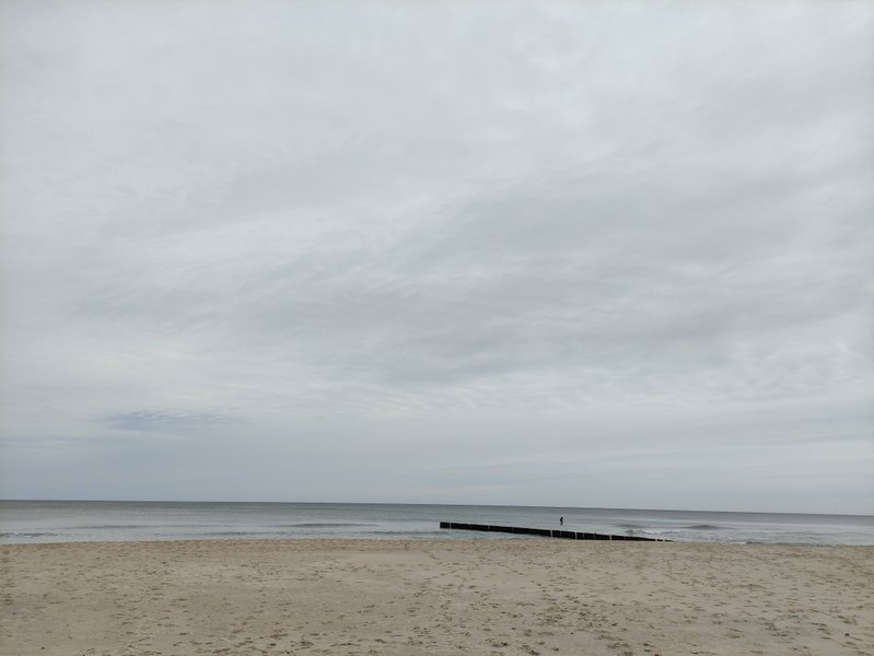 A view of the sandy beach and calm water under a gray, overcast sky. — Władysławowo – Kaper (zatoka), Władysławowo, Pomeranian Voivodeship, Poland