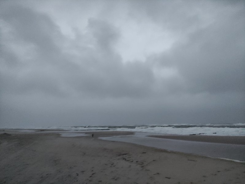 A wide shot of the beach and rough water under a dark, overcast sky. — Władysławowo – Kaper (zatoka), Władysławowo, Pomeranian Voivodeship, Poland