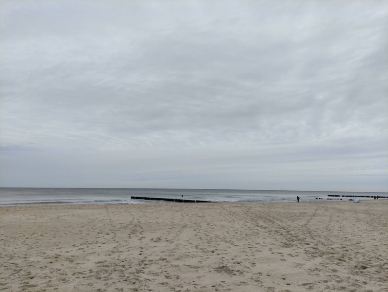 A wide view of the sandy beach and calm sea under an overcast sky. — Władysławowo – Kaper (zatoka), Władysławowo, Pomeranian Voivodeship, Poland