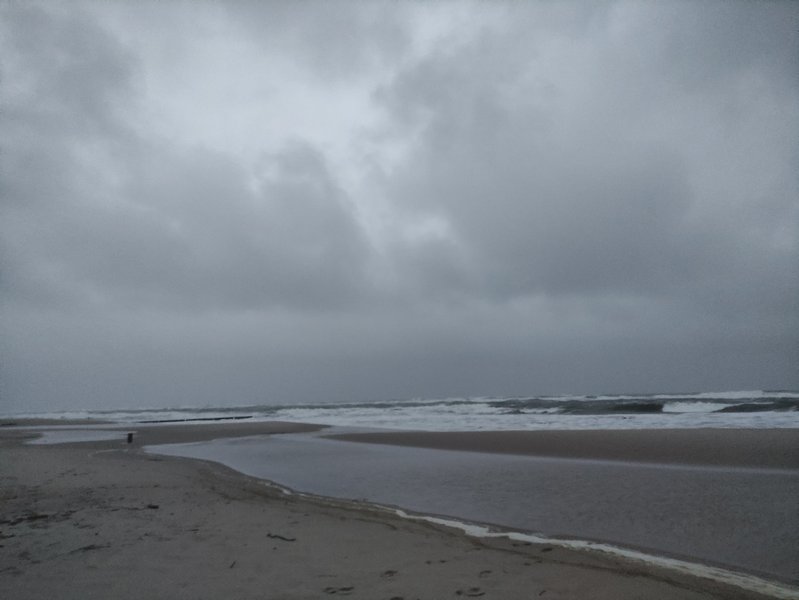 A grey beach with waves under a heavy overcast sky. — Władysławowo – Kaper (zatoka), Władysławowo, Pomeranian Voivodeship, Poland