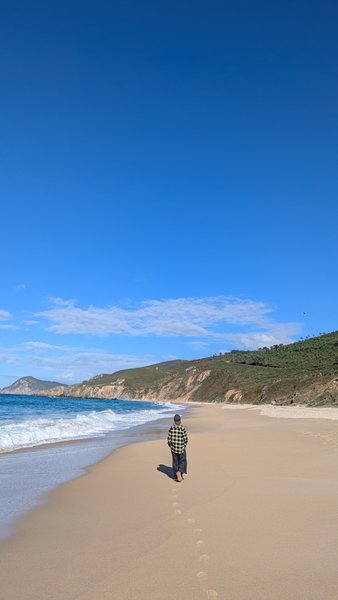 A wide view of Ponzos beach with a person walking along the water's edge. — Ponzos (Ferrol), Covarradeiras, Galicia, Spain