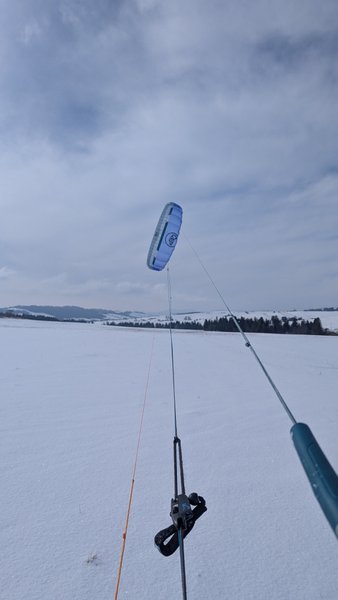 A snowkite flying over the frozen landscape of Kapliczka Orava.