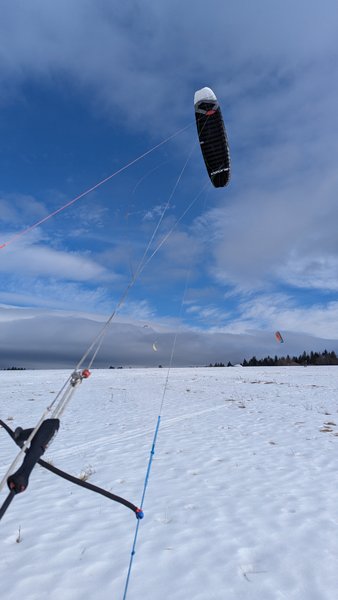 A foil kite being flown over the snow-covered fields at Kapliczka Orava.