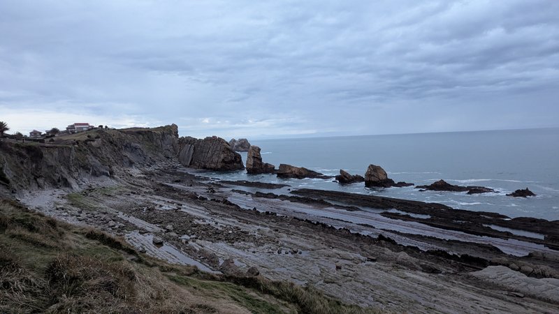 A wide view of the rugged, rocky coastline of Covachos with rock formations in the sea under a cloudy sky. — Covachos (Piélagos), Piélagos, Cantabria, Spain