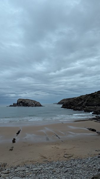 A cloudy day view of a sandy beach with rocky shores and an offshore island. — Covachos (Piélagos), Piélagos, Cantabria, Spain