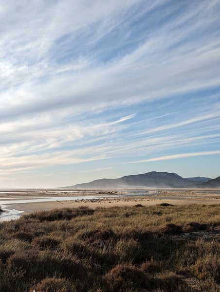 A wide landscape view of the Rio Jara lagoon and its surrounding sandbanks under a wispy sky.